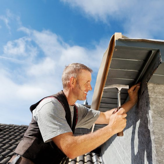 A Roofer Nails in Roofing Material.