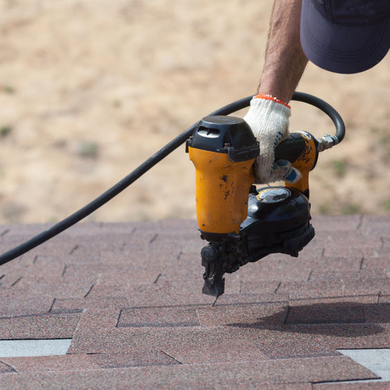 A Roofer Nailing Asphalt Shingles Down.