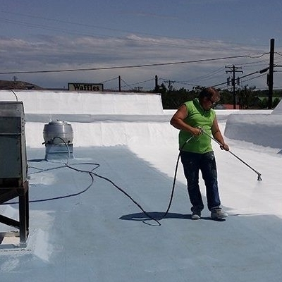 A Roofer Sprays on Roof Coating.