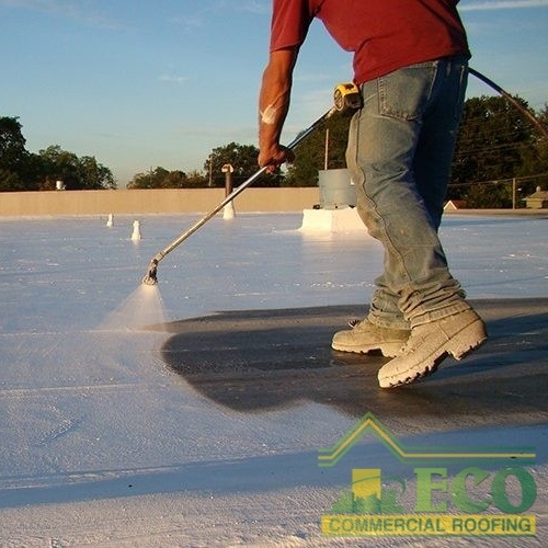 A Roofer Coats a Flat Roof.