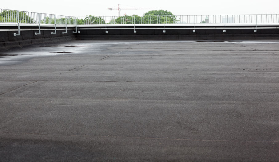 an flat roof with roofing and fencing