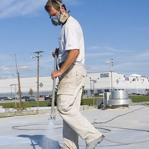 A Roofer Applies Flat Roof Restoration Coating.