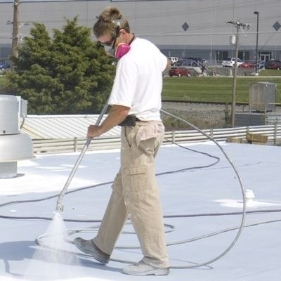 A Roofer Sprays on a Commercial Roof Coating. 